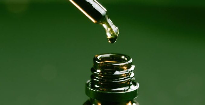 pipette mettant une goutte dans une fiole d'huile de cbd